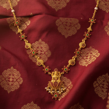 Gold toned necklace with green gemstones on a red fabric background