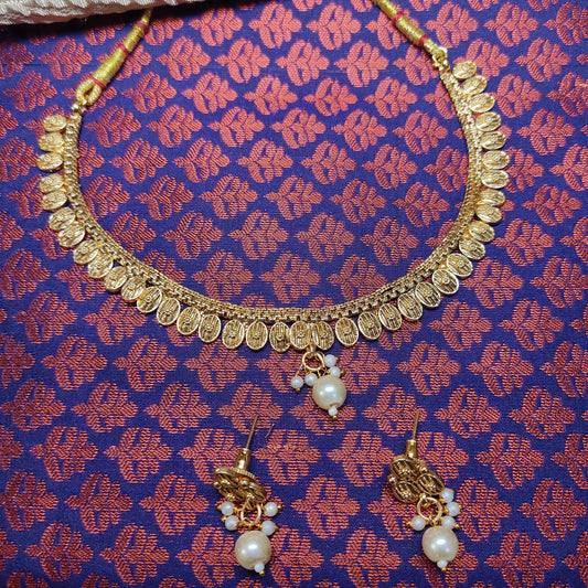 Gold toned necklace and earrings set on a patterned fabric background