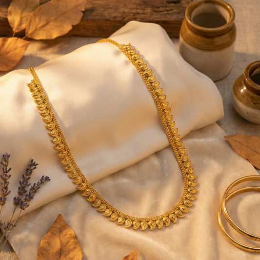 Gold plated necklace on a beige fabric with dried leaves and pots in the background
