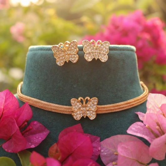 Butterfly-themed jewelry set on a green velvet stand with pink flowers in the background