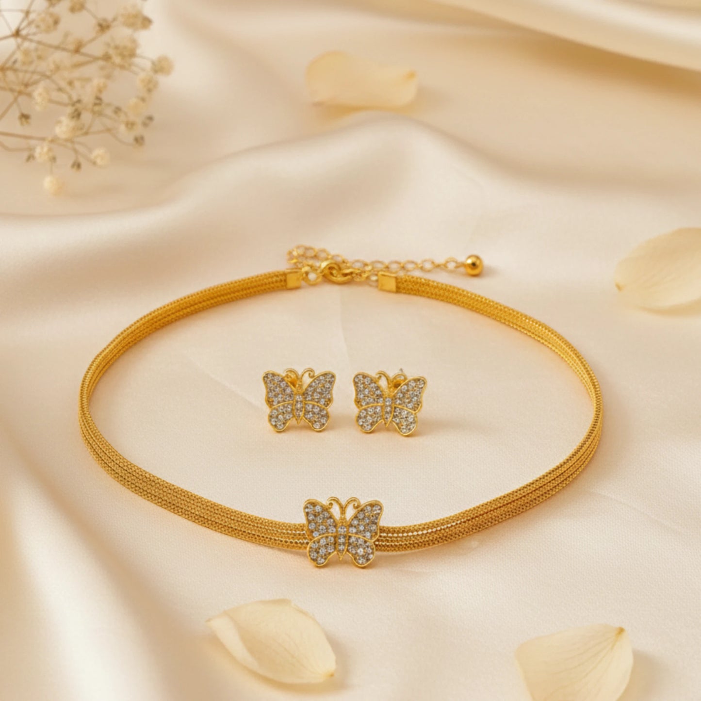 Gold toned butterfly-themed jewelry set on a soft beige fabric background