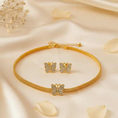 Gold toned butterfly-themed jewelry set on a soft beige fabric background