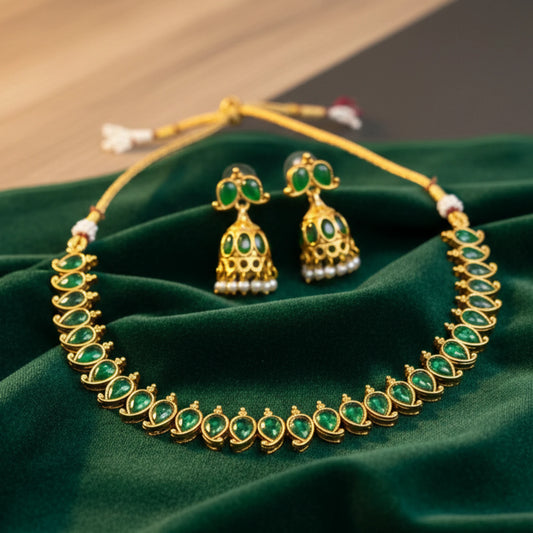 Antique Gold finish necklace with green gemstones and matching earrings on a green fabric background