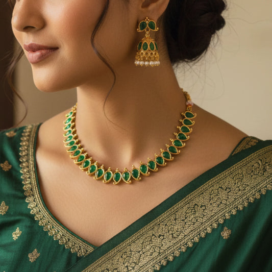 Woman wearing a green and gold traditional outfit with a matching necklace and earrings.
